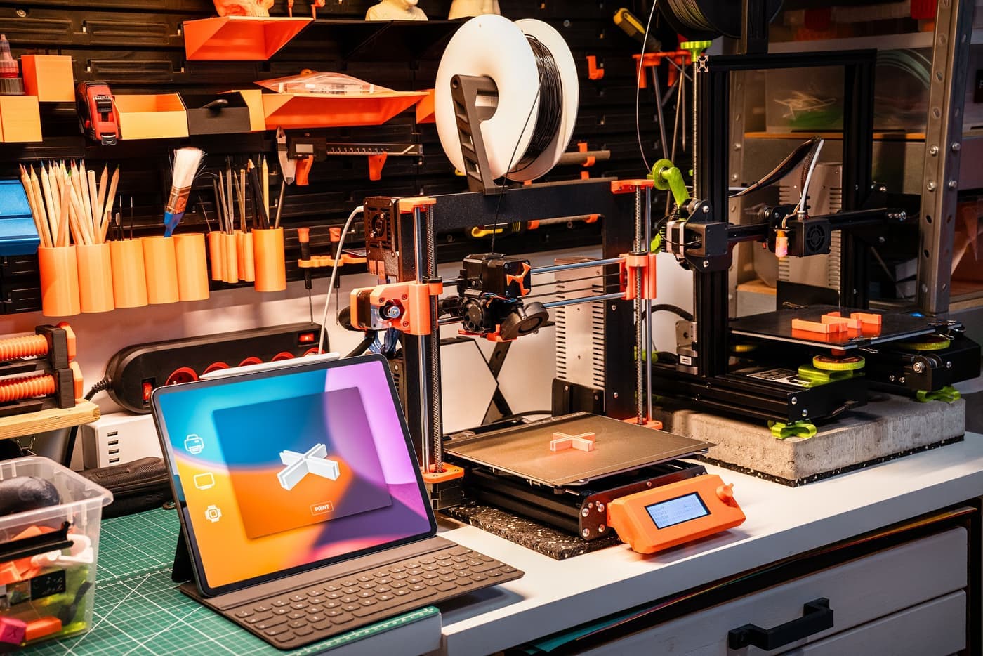 A desktop 3D printer on a warm-lit workshop bench beside spools of filament
