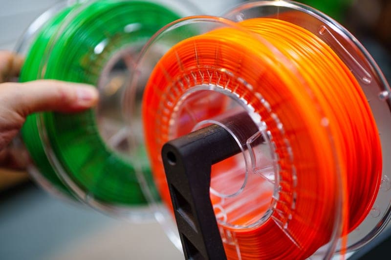A stack of multicolored filament spools representing a four-spool material system
